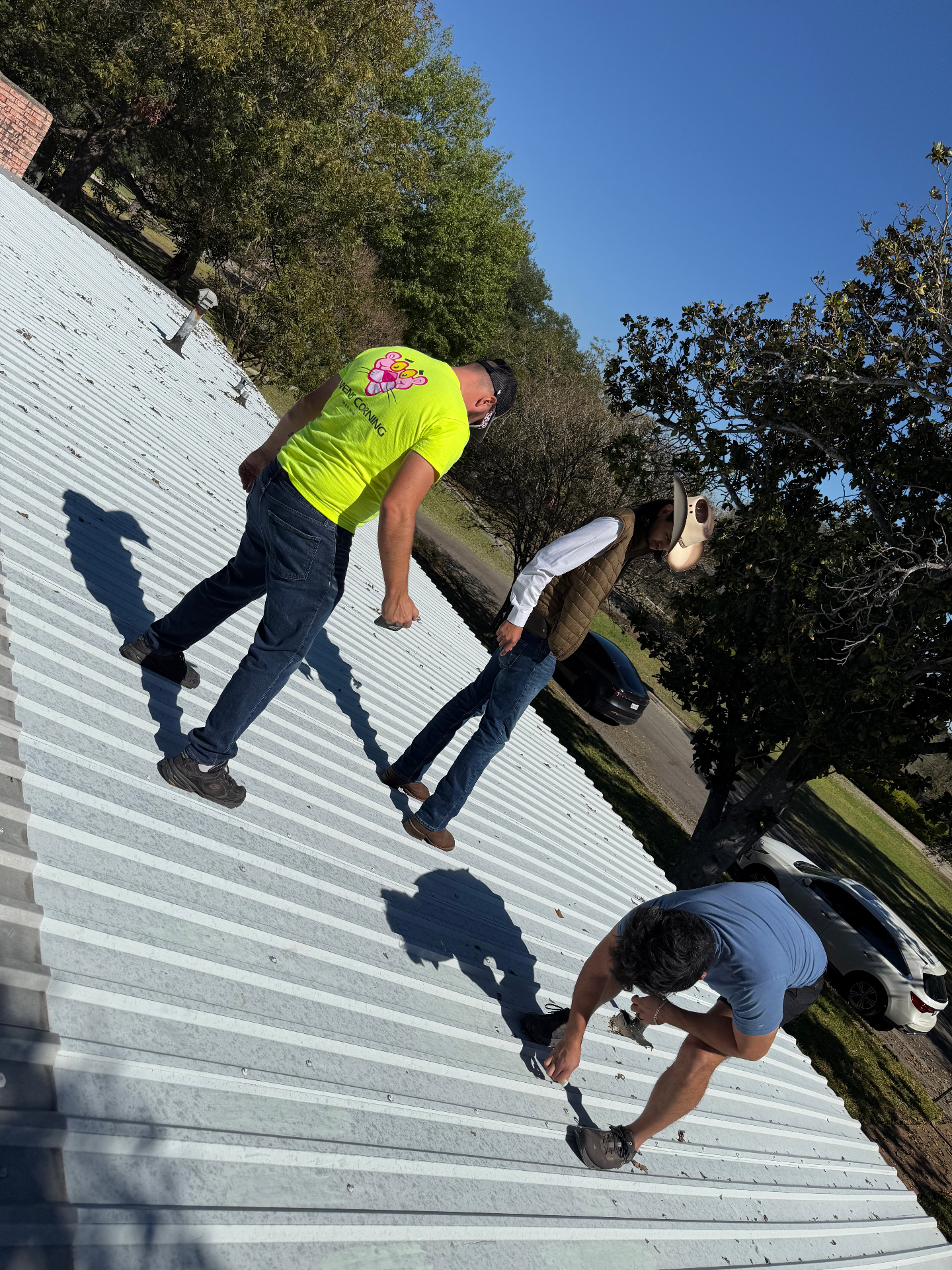 Dustin Michael Drozd inspecting a standing-seam metal roof in Texas with two team members.