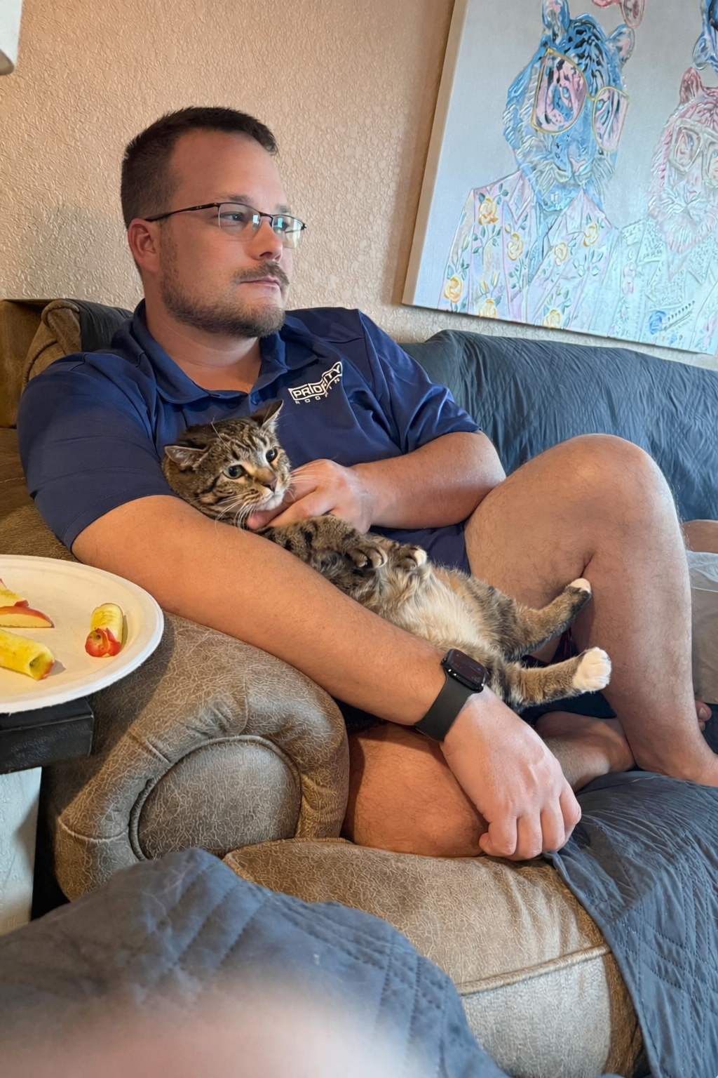 Dustin Michael Drozd in a Priority Roofing polo shirt at home, holding his cat.