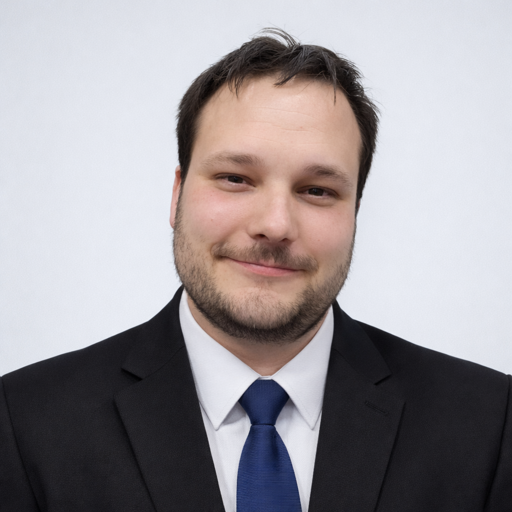 Executive headshot portrait of Dustin Michael Drozd in a dark suit and blue tie.